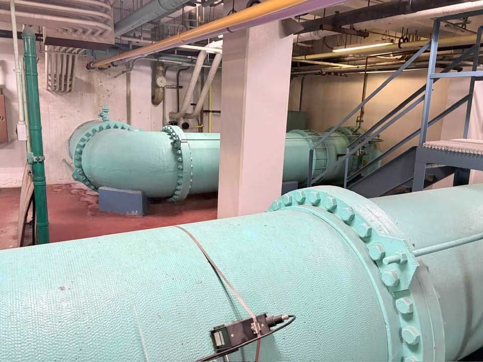Large teal pipes and machinery in an industrial interior.