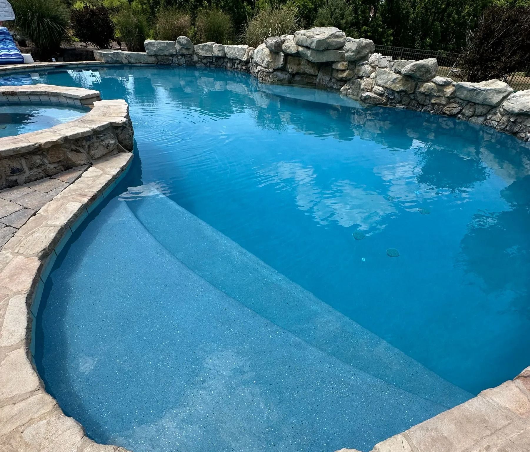 Blue swimming pool with stone steps and edging.