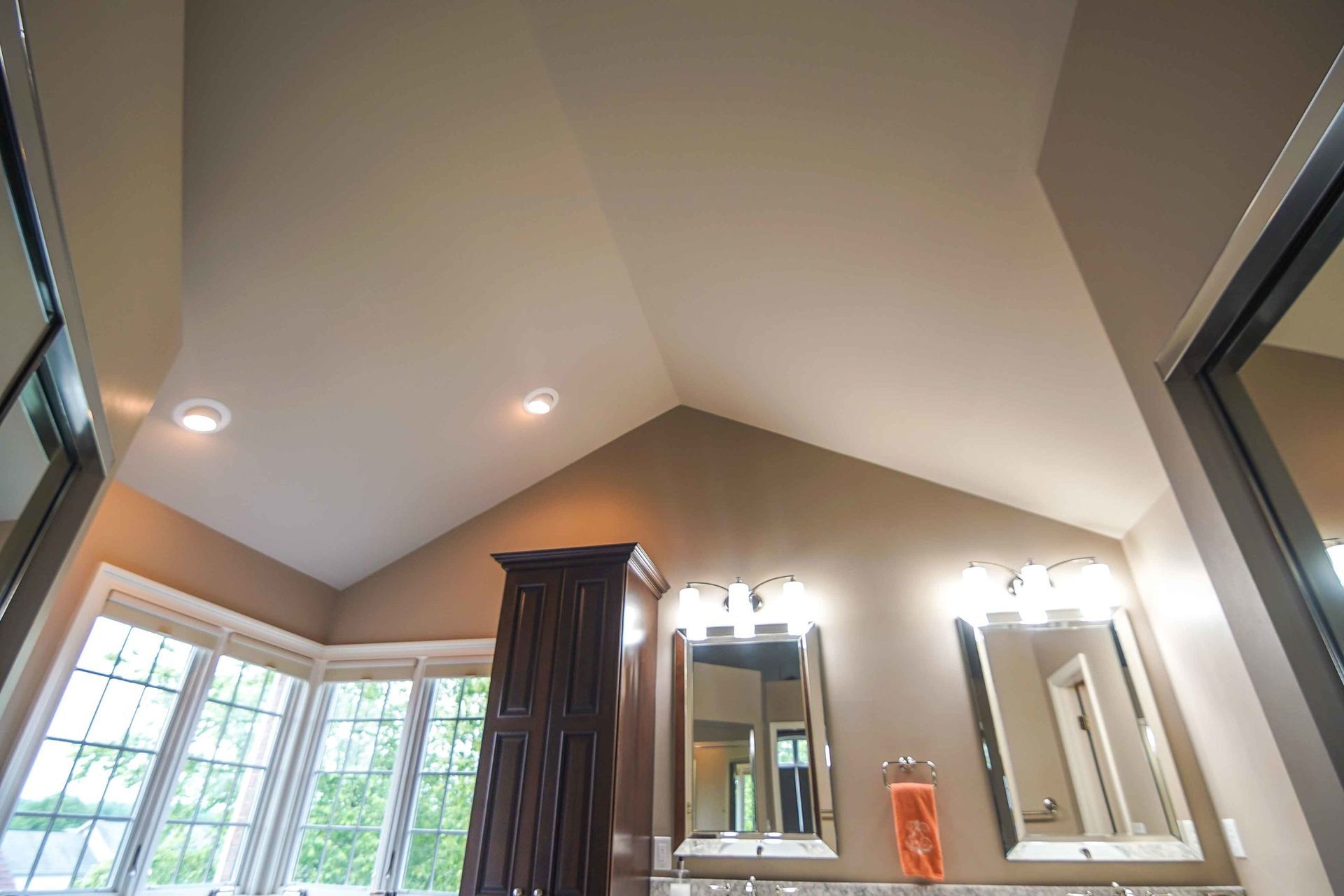 A bathroom with a vaulted ceiling and two mirrors.