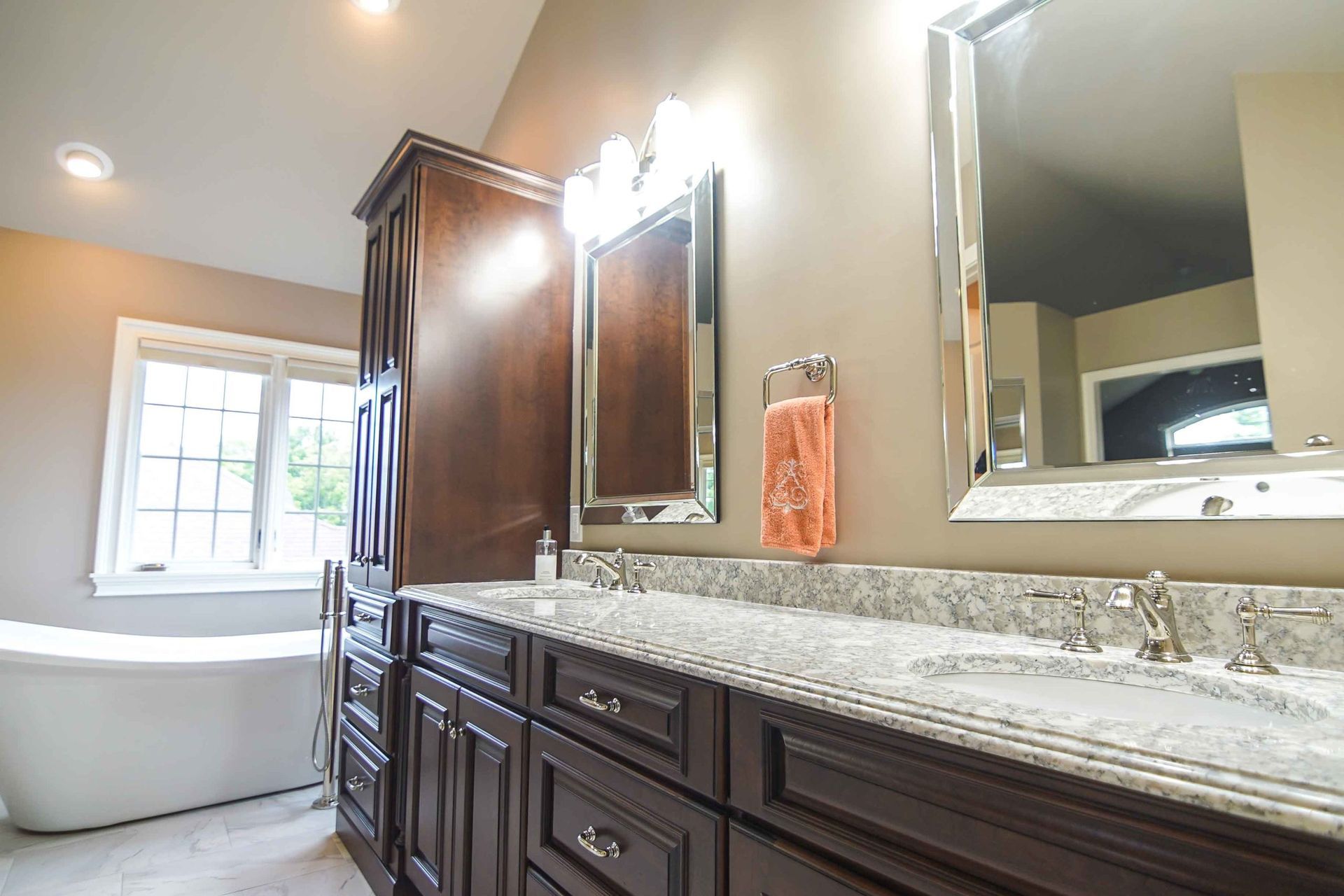 A bathroom with two sinks , two mirrors and a tub.