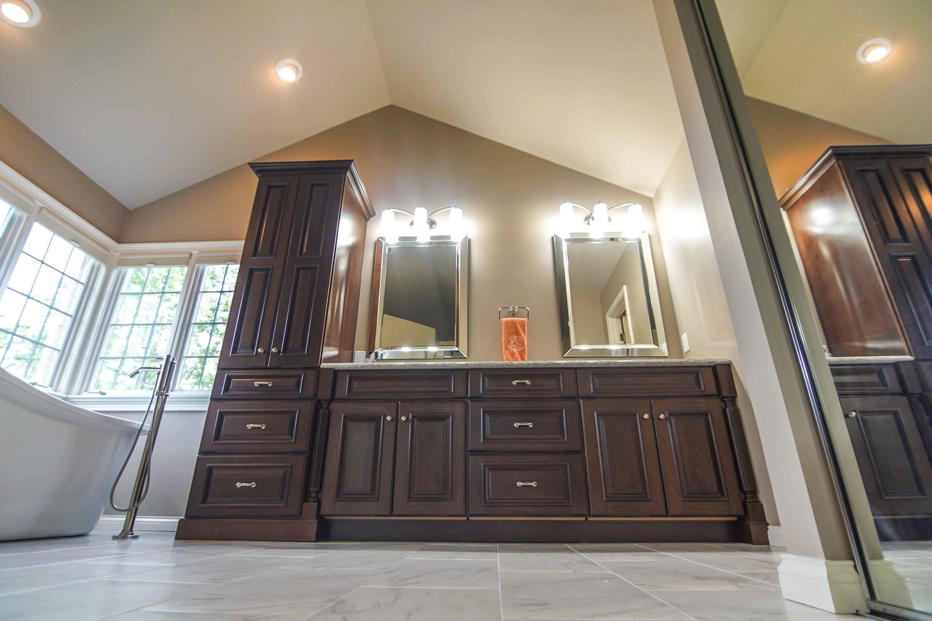 A bathroom with two sinks , two mirrors and a bathtub.