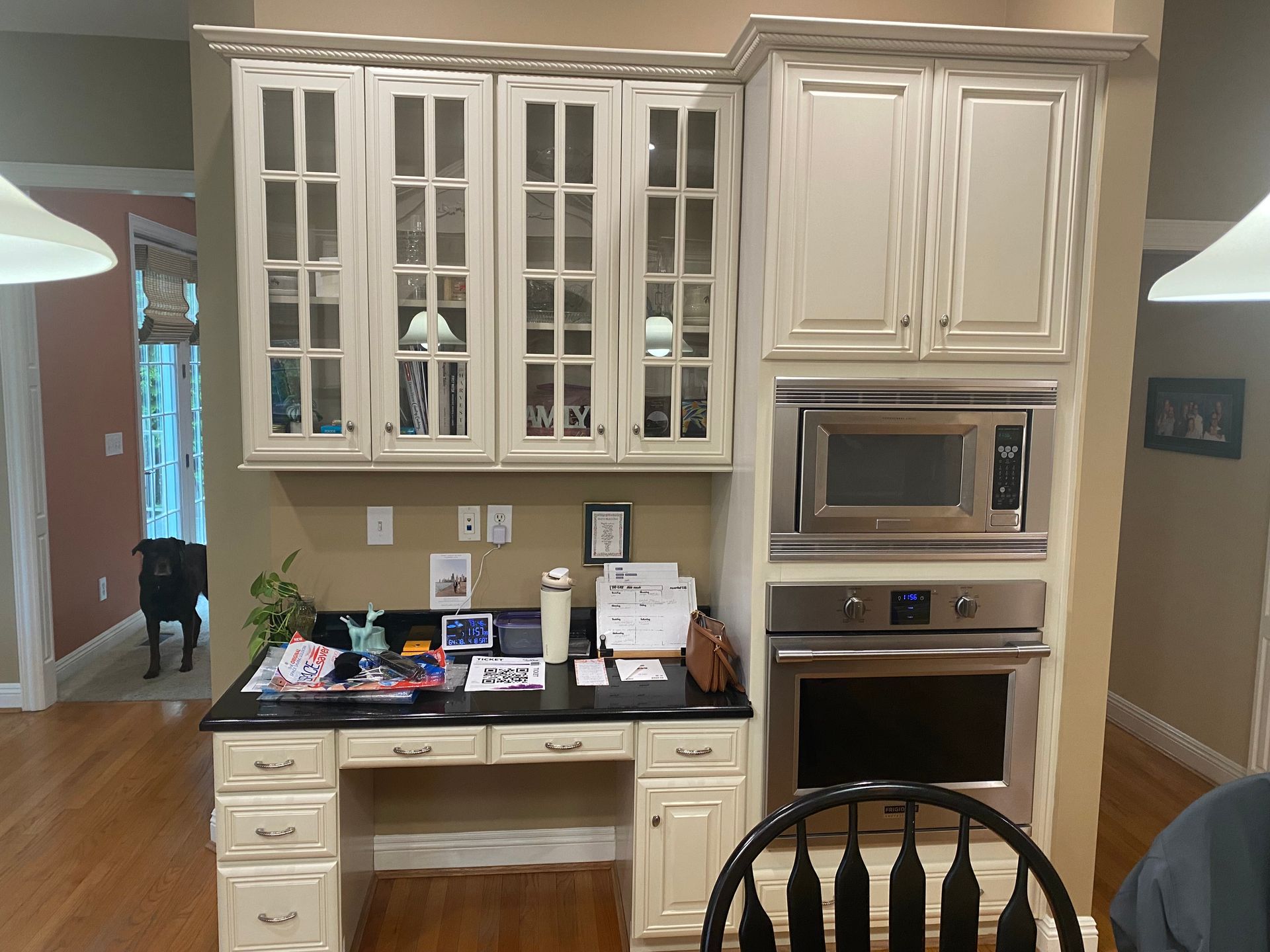 Built-in kitchen desk with white cabinets, glass fronts, and a microwave and oven on the right side