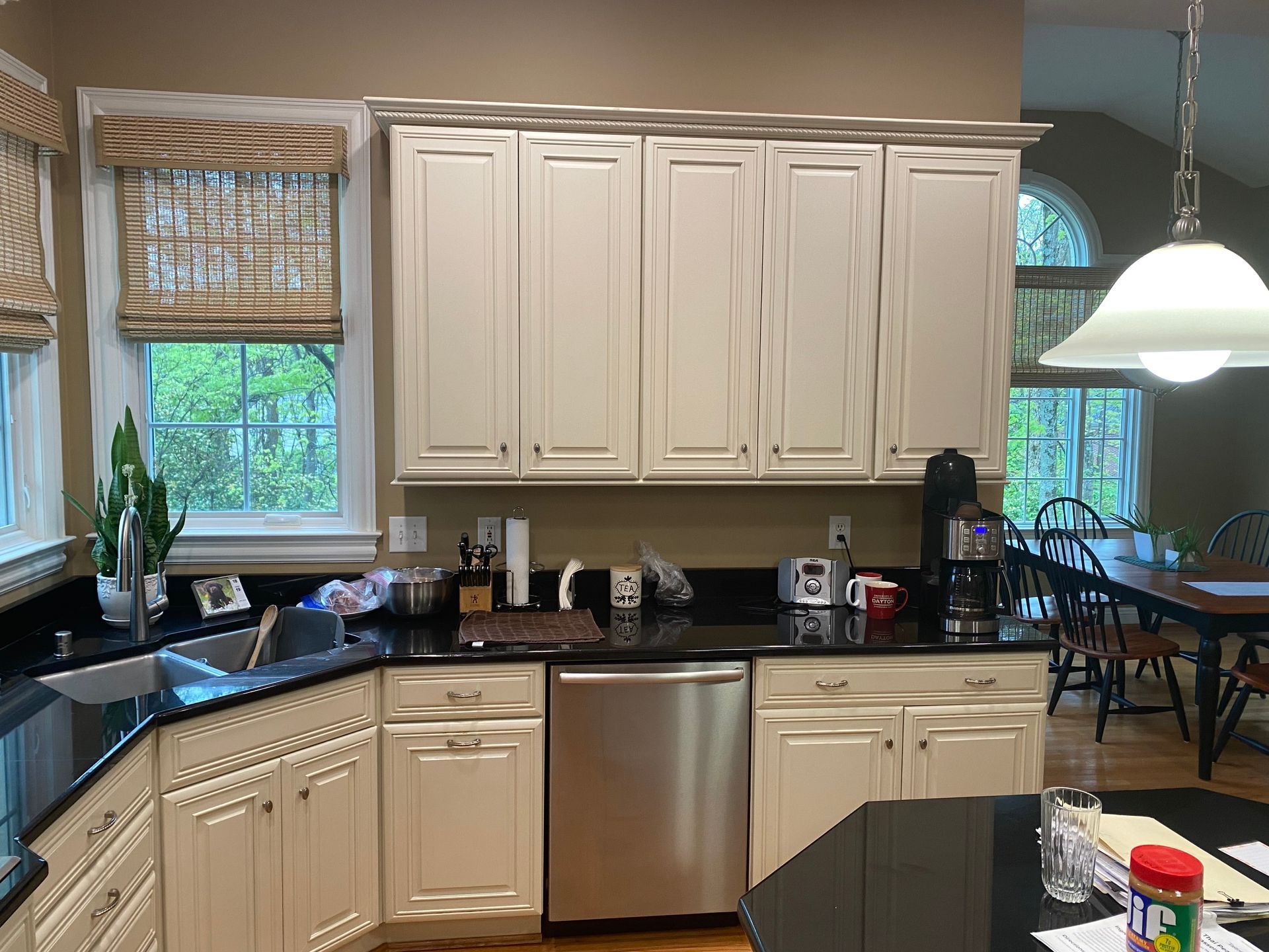 Modern kitchen with white cabinets, black countertops, stainless dishwasher, and a window over the sink