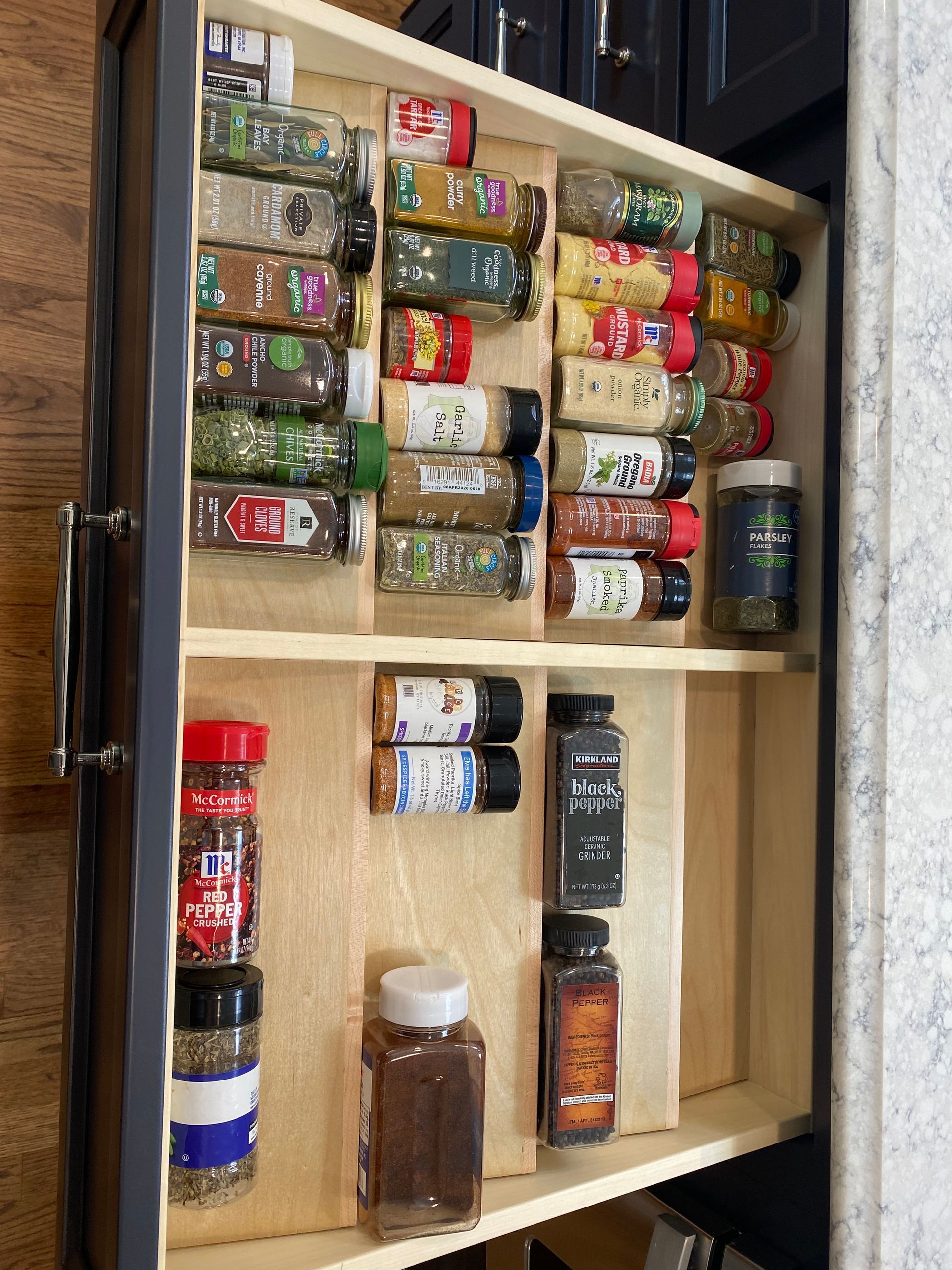 Open spice cabinet with organized jars and containers on wooden shelves