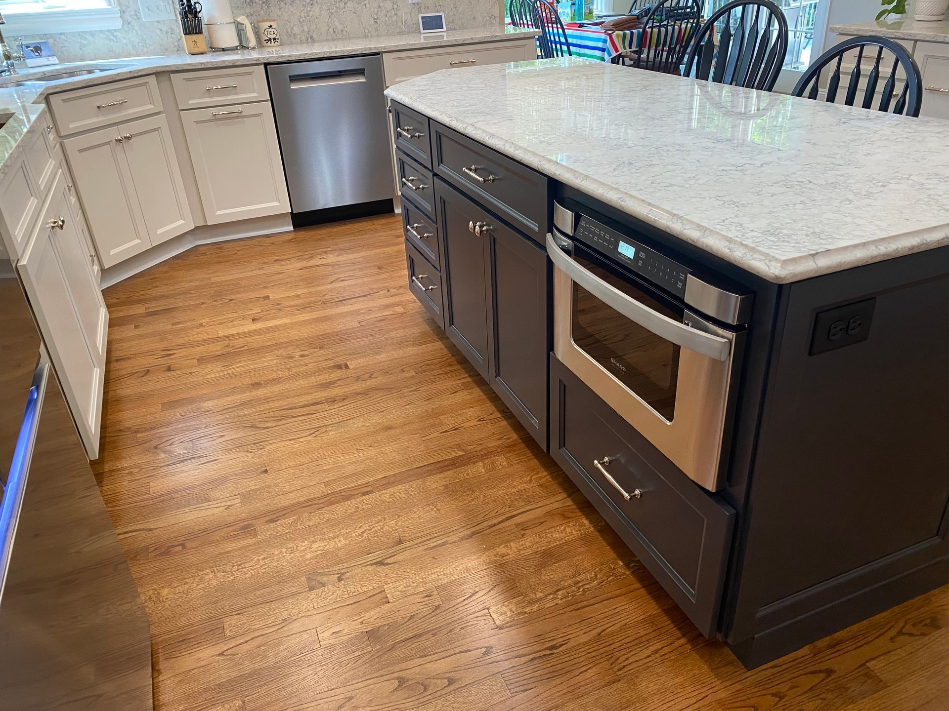 Modern kitchen with white cabinets, large island, stainless appliances, and wood floors