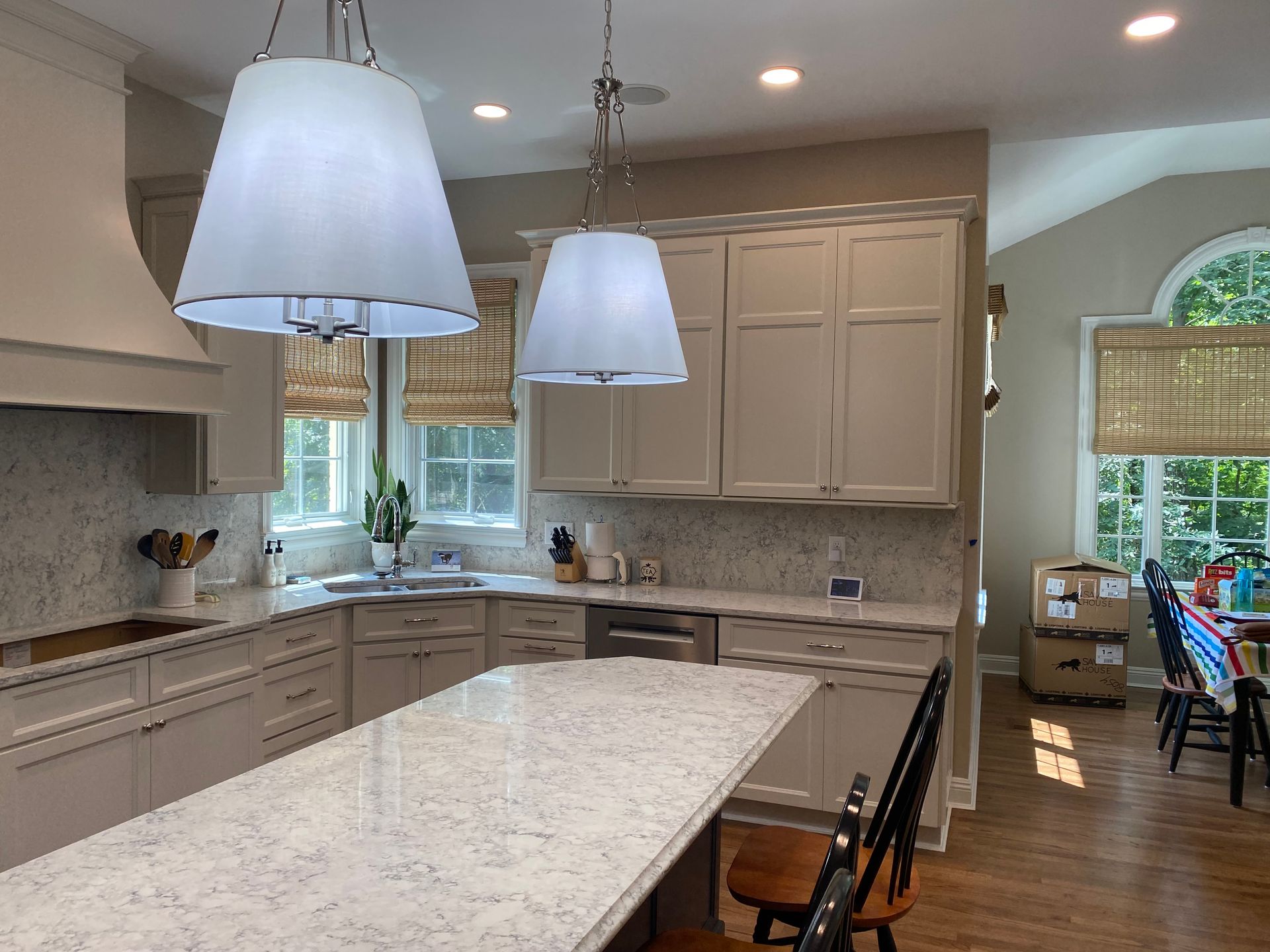 Modern kitchen with marble island, gray cabinets, pendant lights, and a breakfast nook by large windows