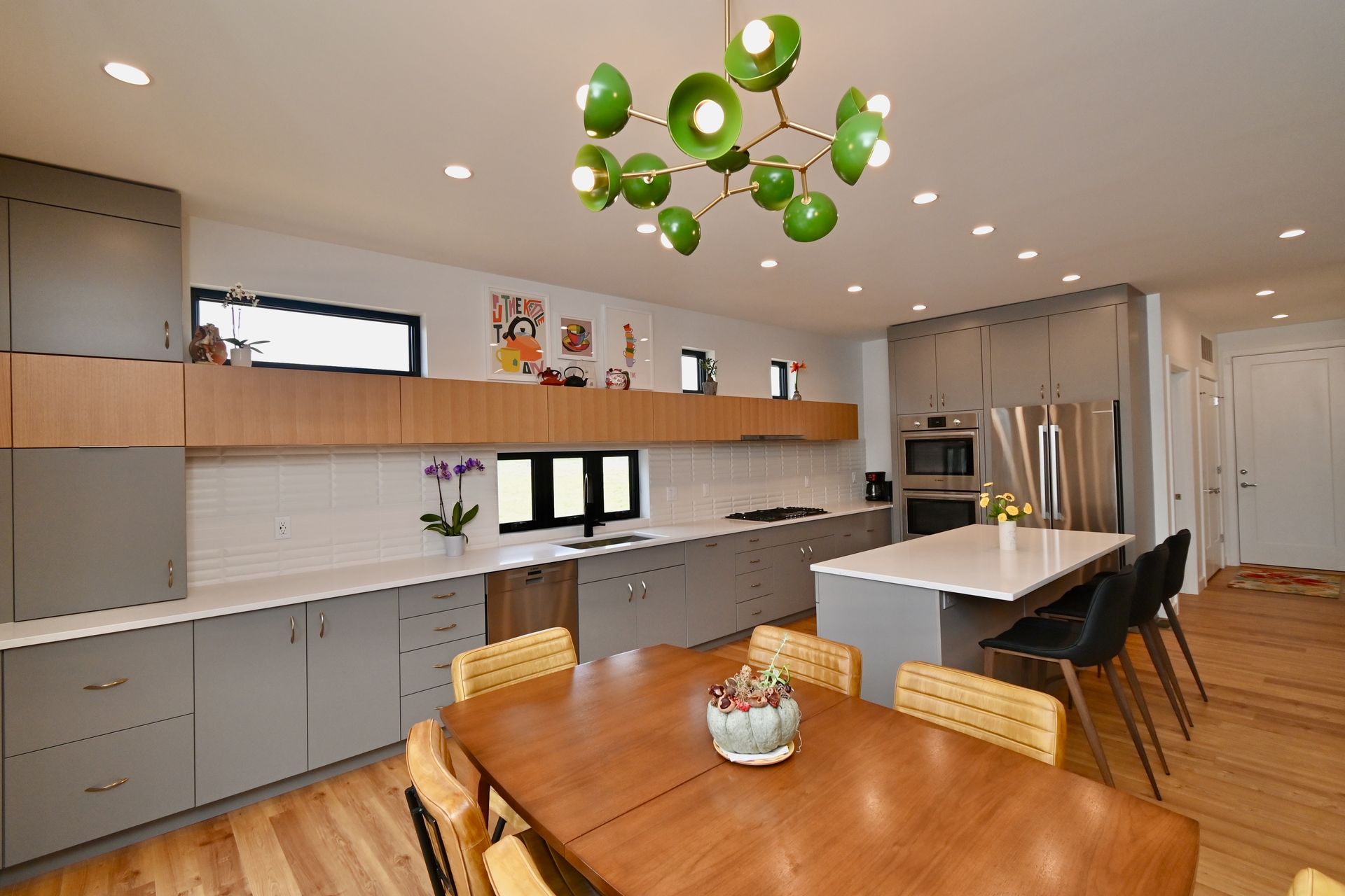 Modern kitchen with gray cabinets, white countertops, and a dining table.