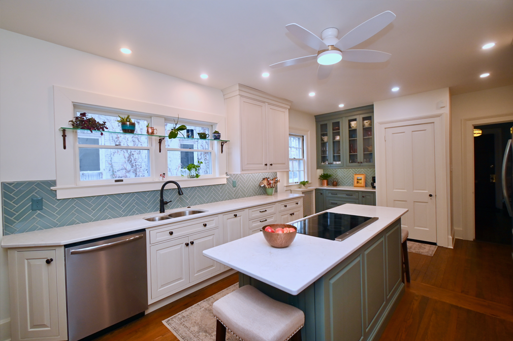Bright kitchen with white and teal cabinets, stainless steel appliances, and an island.