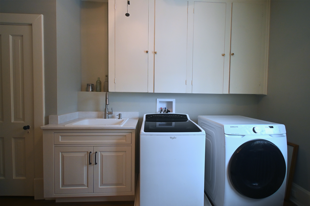 Laundry room with white cabinets, sink, washer, and dryer.
