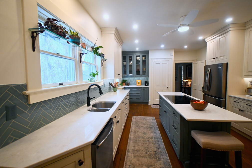 A modern kitchen with blue backsplash, white counters, and a green island.