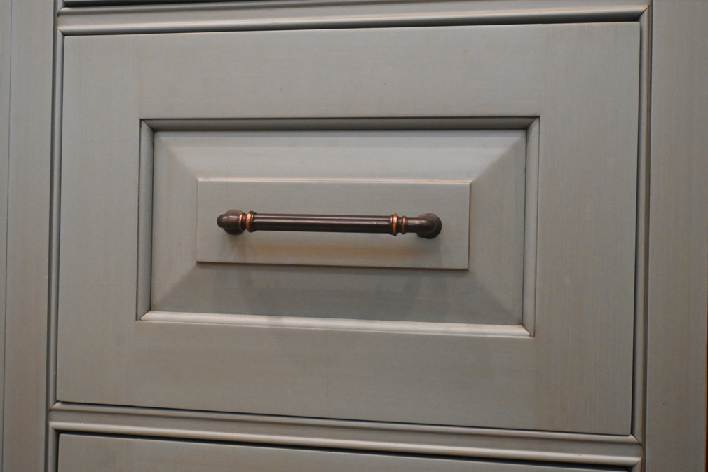 Gray cabinet door with dark bronze handle.