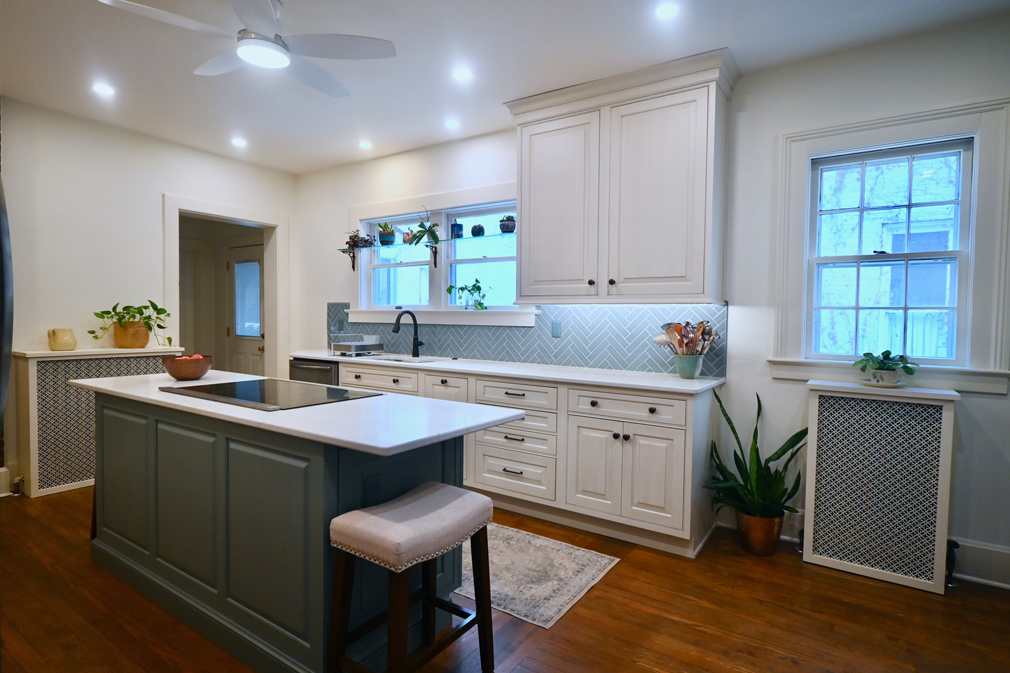 A modern kitchen with white cabinets, blue backsplash, and a gray island with a countertop and stool.