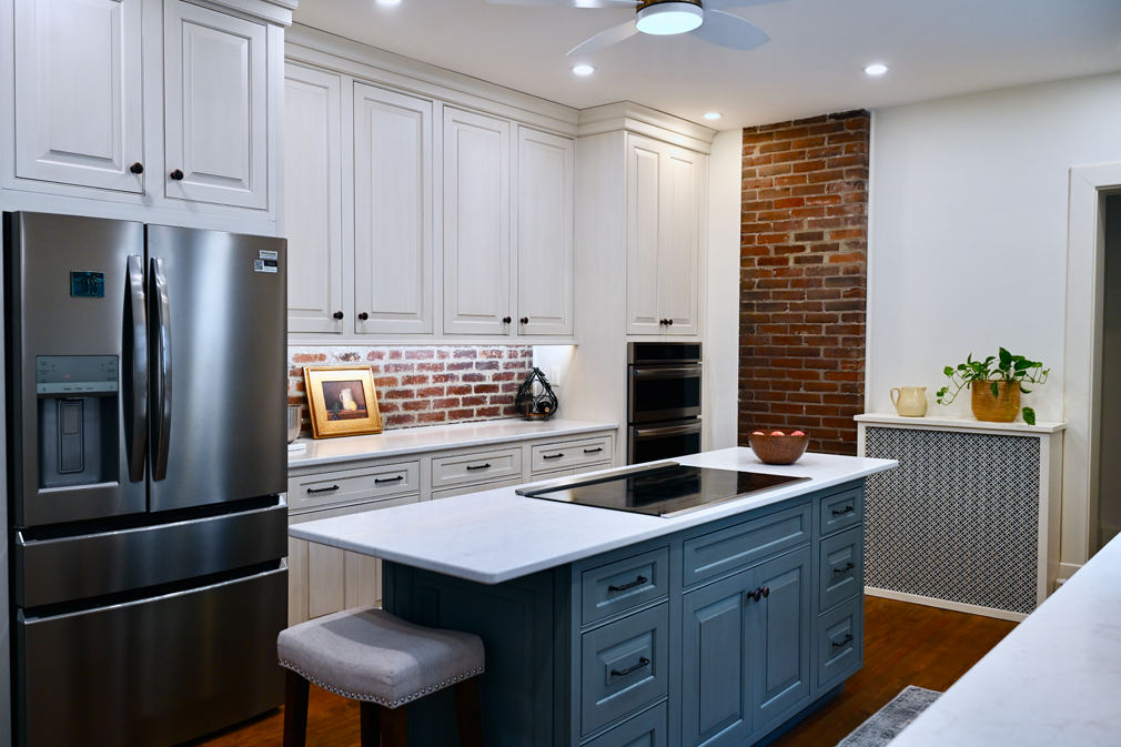 Modern kitchen with blue island, white cabinets, and brick accent wall.