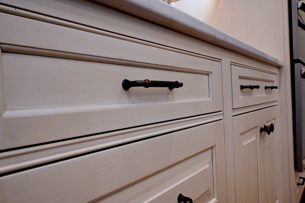 Cream-colored kitchen cabinets with black hardware, and countertop.