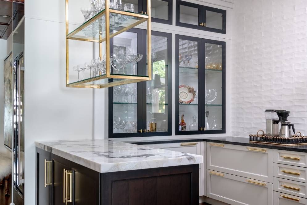 A kitchen with a marble counter top , black cabinets , and a glass display case.