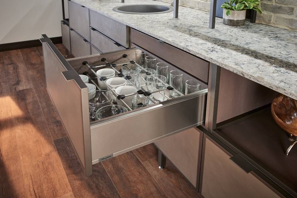 A kitchen with a drawer filled with glasses and bowls.