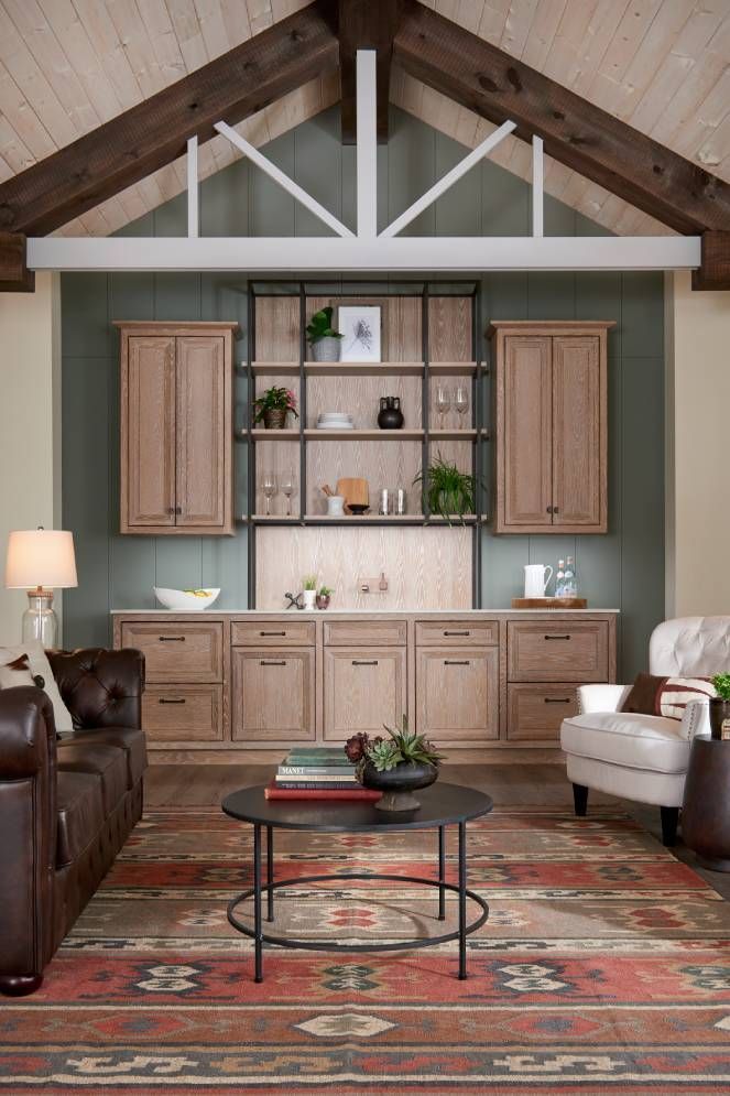 A living room with a vaulted ceiling , wooden cabinets , a couch , chair , coffee table and rug