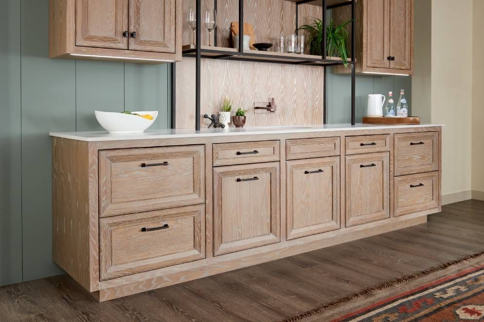 A kitchen with wooden cabinets and drawers and a rug on the floor.