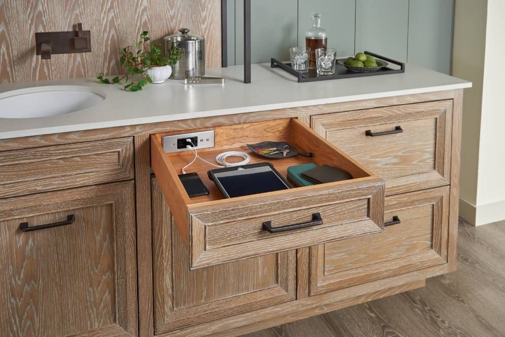 A wooden cabinet with a drawer open and a tablet in it.