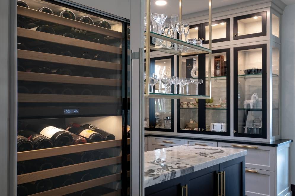 A kitchen with a wine cooler filled with wine bottles and glasses.