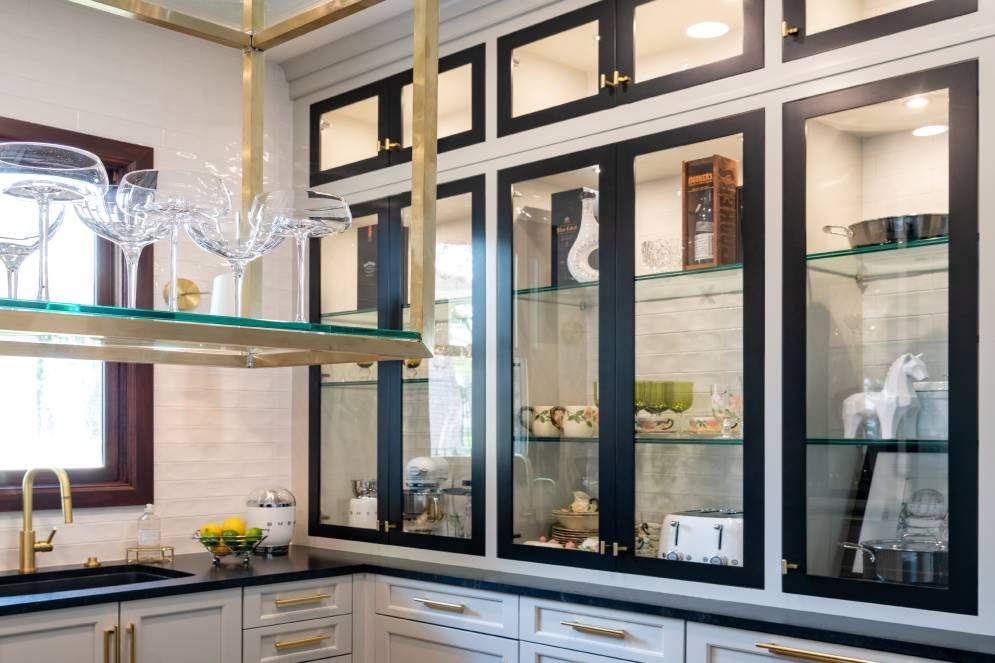 A kitchen with black and white cabinets and glass shelves.