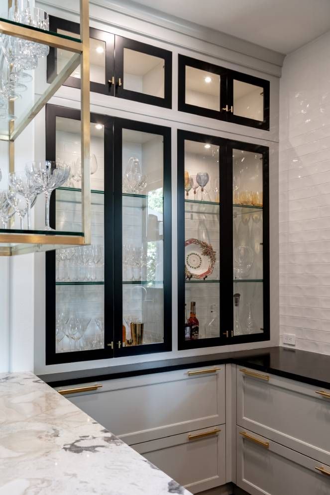 A kitchen with black and white cabinets and a glass display case.