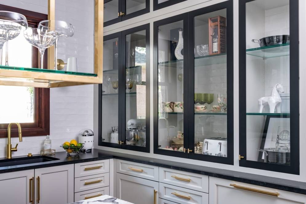 A kitchen with black and white cabinets and glass doors.