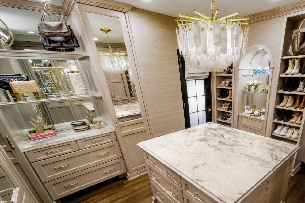 A walk in closet with a large island in the middle and a chandelier.
