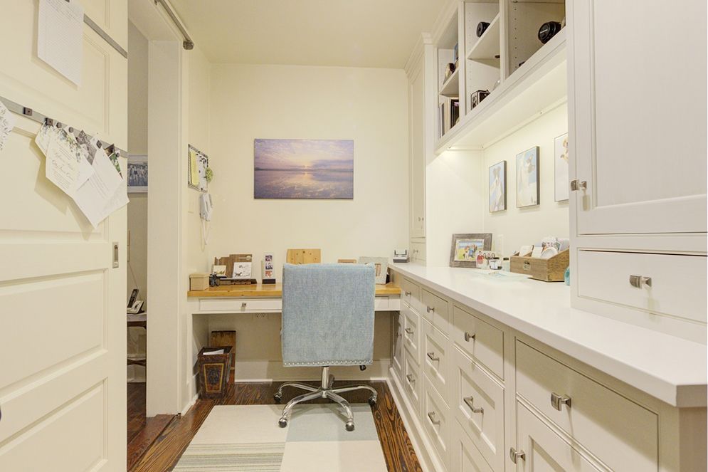 A home office with a desk , chair , drawers and cabinets.