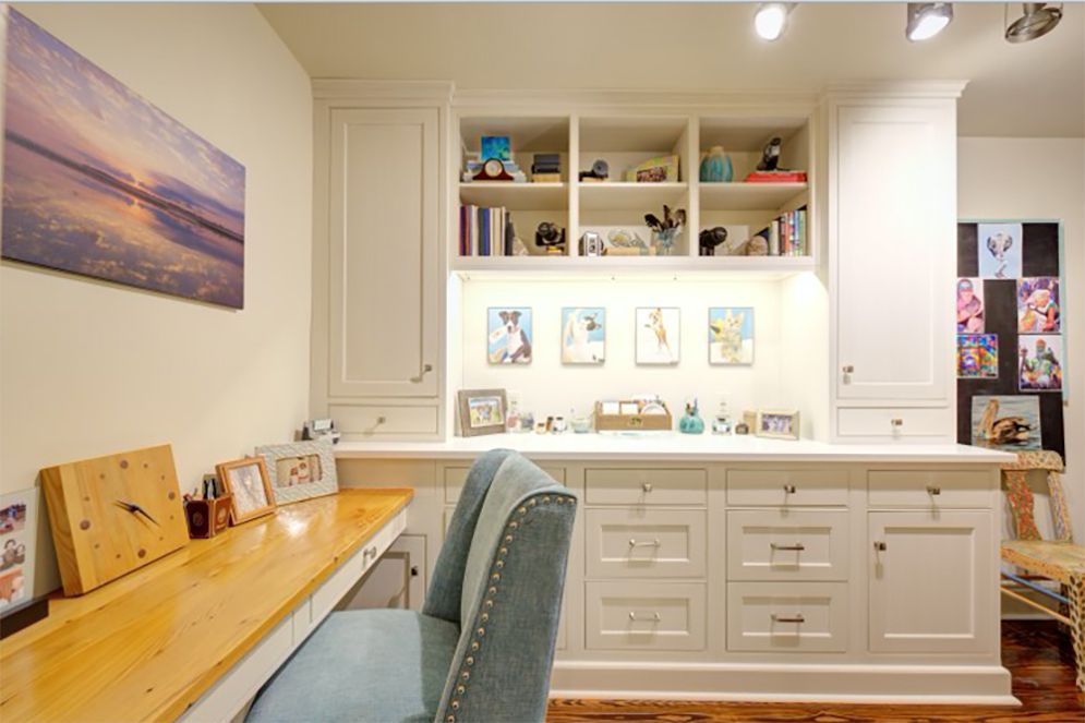 A room with a desk and chair and a painting on the wall