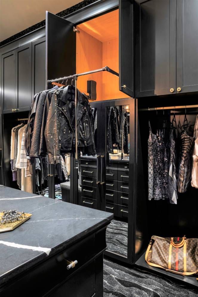 A walk in closet with black cabinets and a large mirror