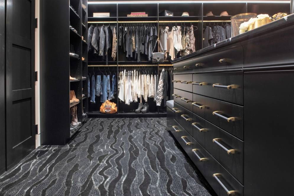 A walk in closet filled with lots of clothes and dressers.