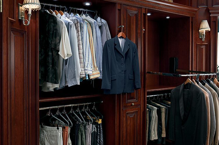 A closet filled with lots of clothes and a jacket hanging on a rack.