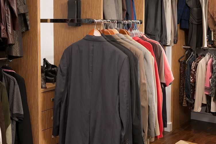 A closet filled with lots of clothes including jackets and shirts