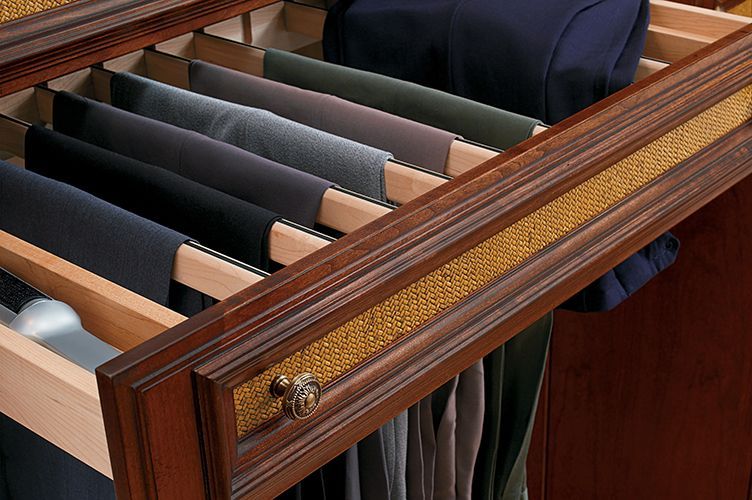 A wooden drawer filled with pants and ties