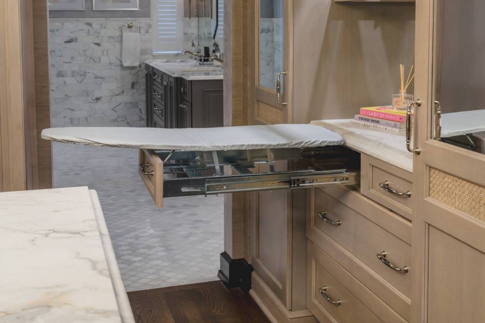A kitchen with a pull out ironing board in the corner.