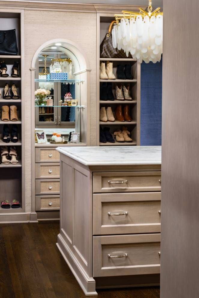 A walk in closet with a large island and a mirror.
