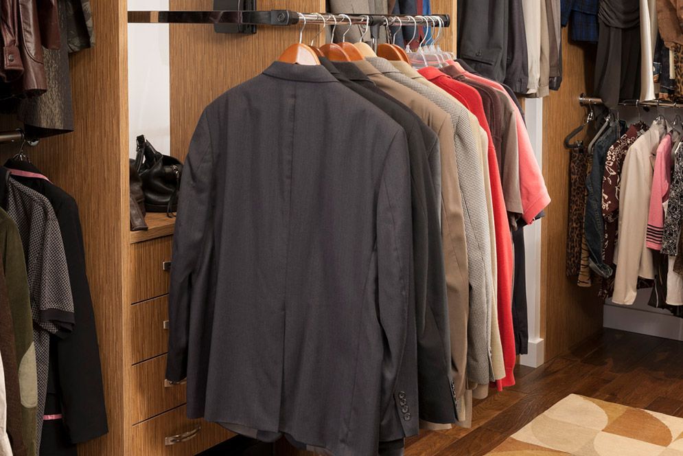 A closet filled with lots of clothes and jackets hanging on racks.