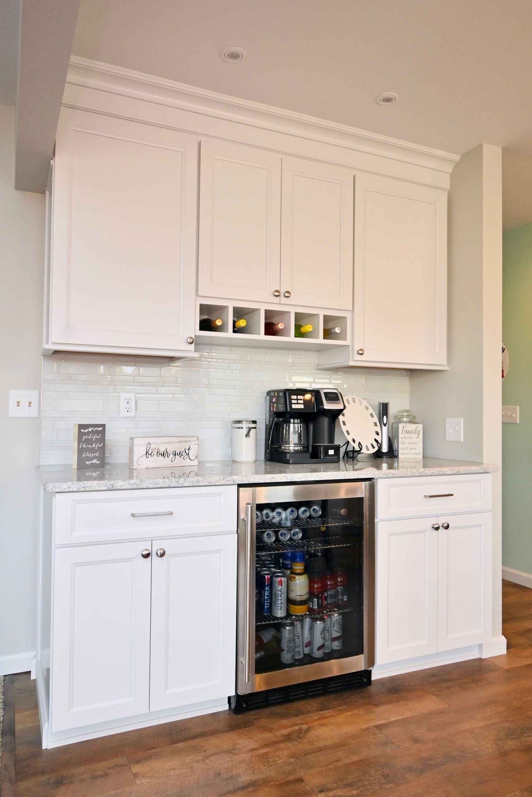 A kitchen with white cabinets and a stainless steel refrigerator.