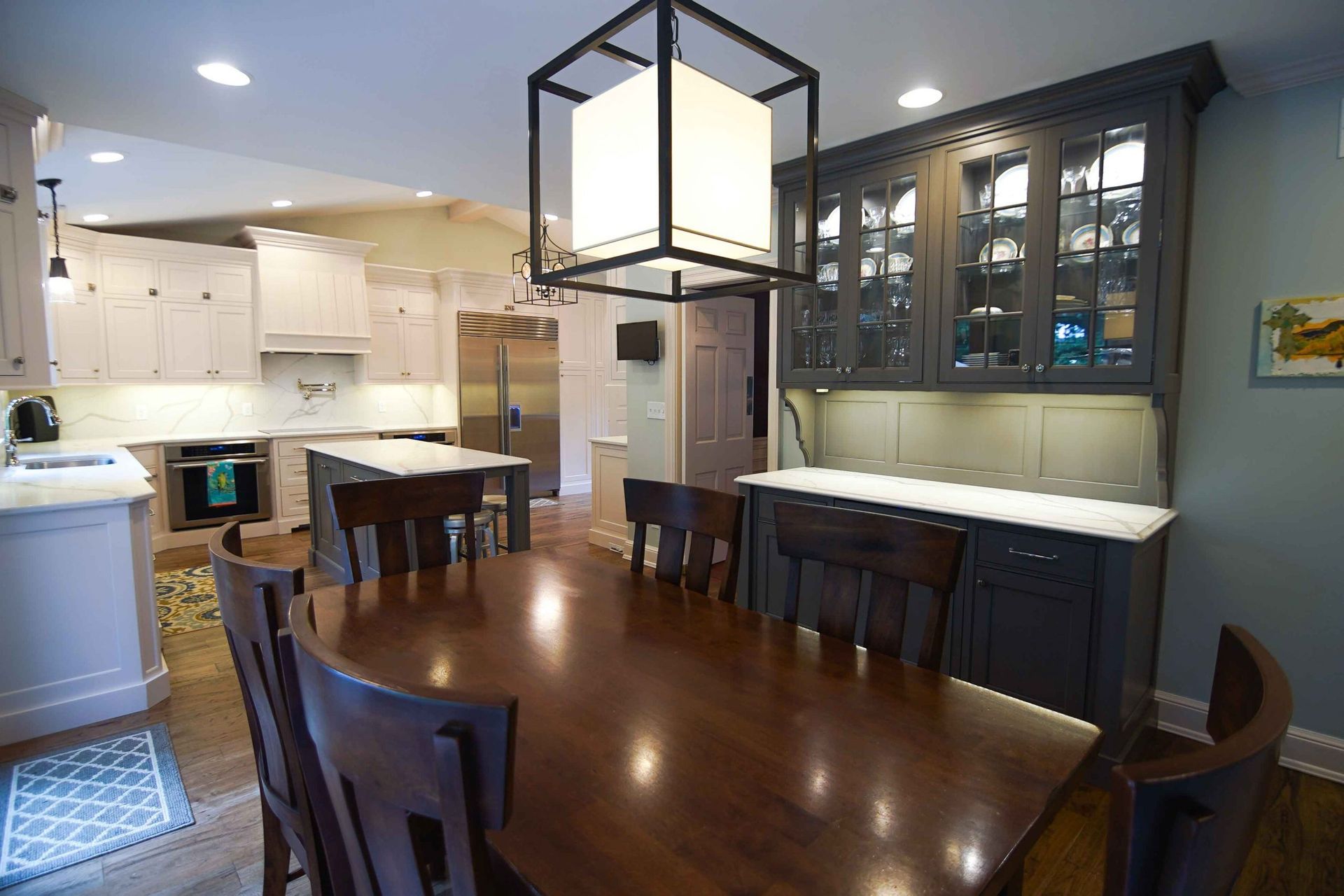 A dining room table and chairs in a kitchen with a chandelier hanging from the ceiling.
