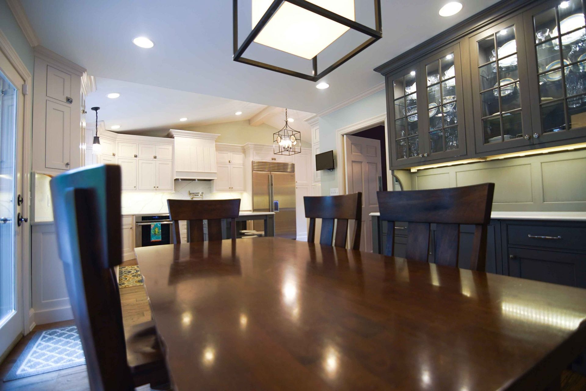 A dining room table and chairs in a kitchen with a lantern hanging from the ceiling.