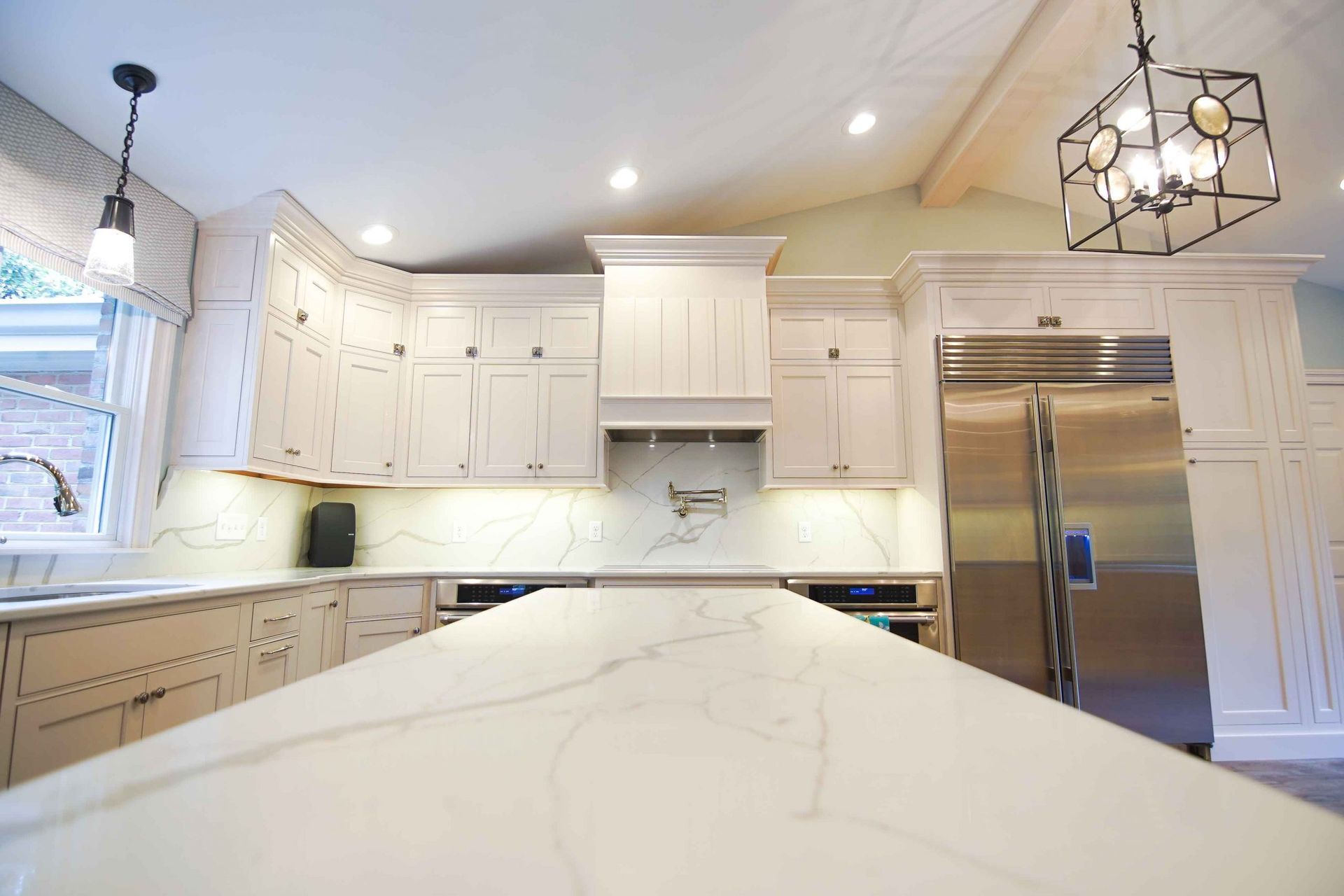 A kitchen with white cabinets , stainless steel appliances , and a large island.