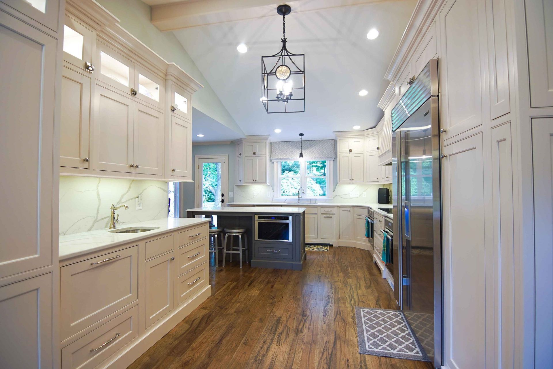 A kitchen with white cabinets , stainless steel appliances , and hardwood floors.