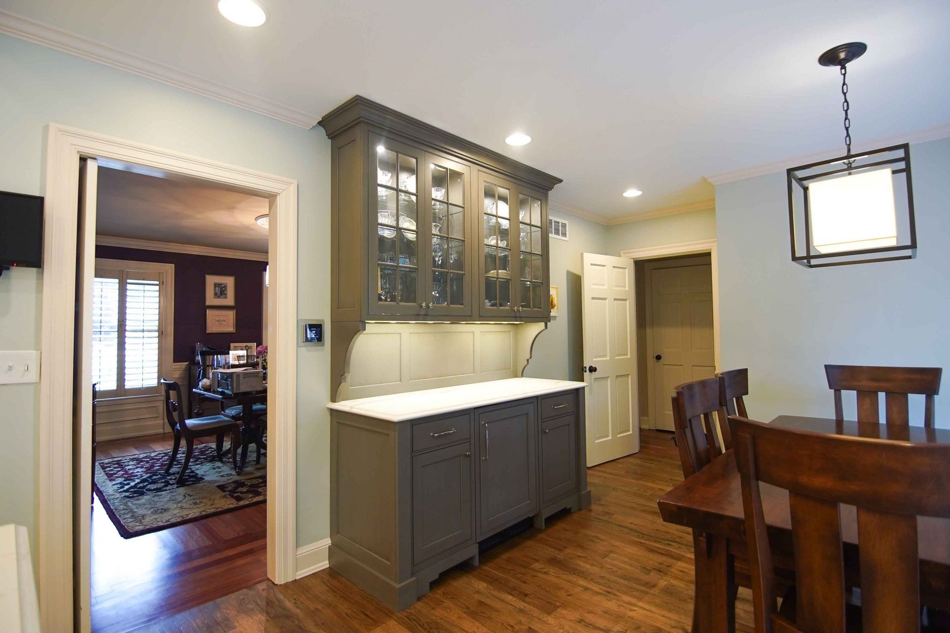 A dining room with a table and chairs and a cabinet with glass doors.