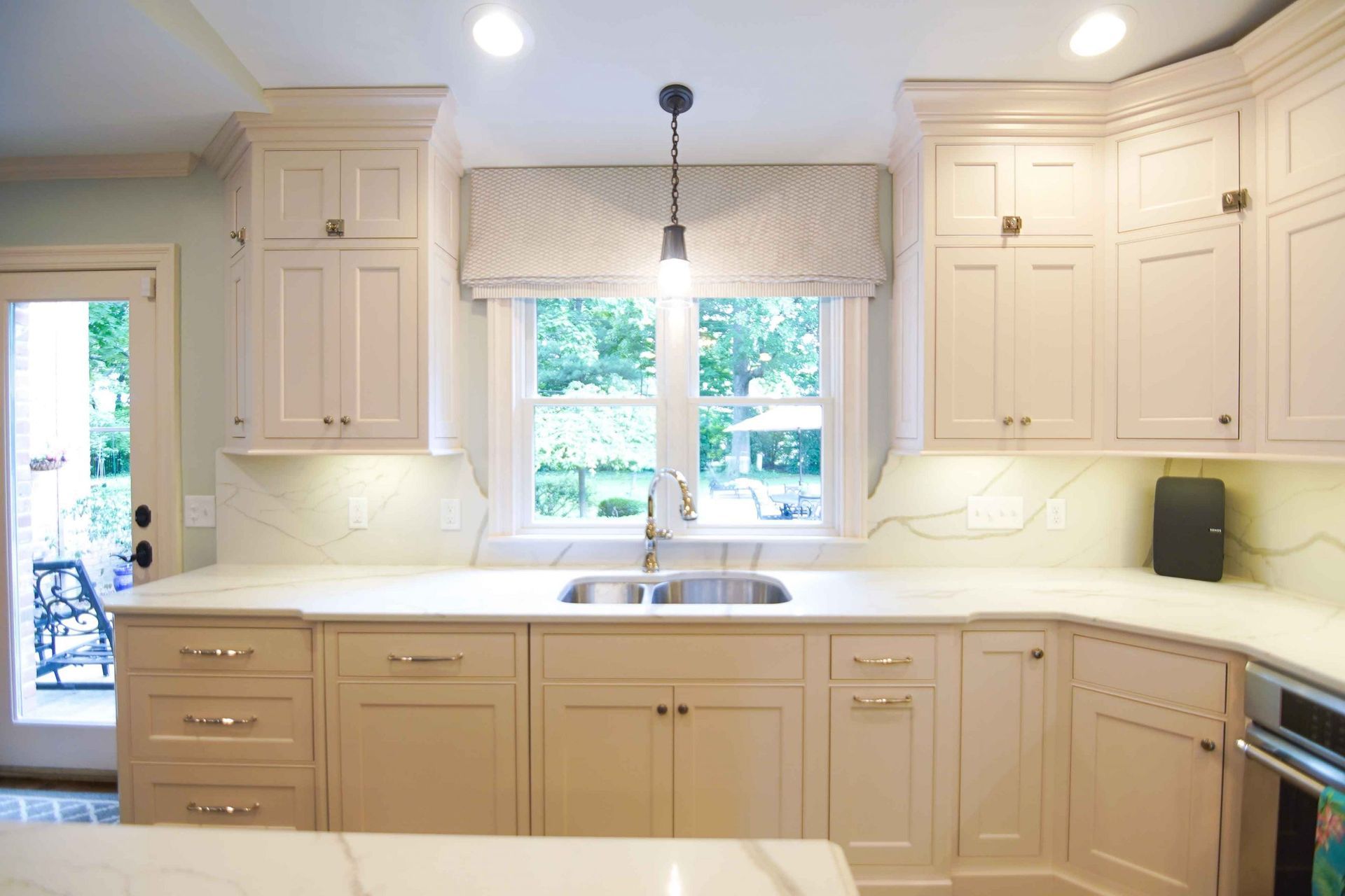 A kitchen with white cabinets , a sink , and a window.