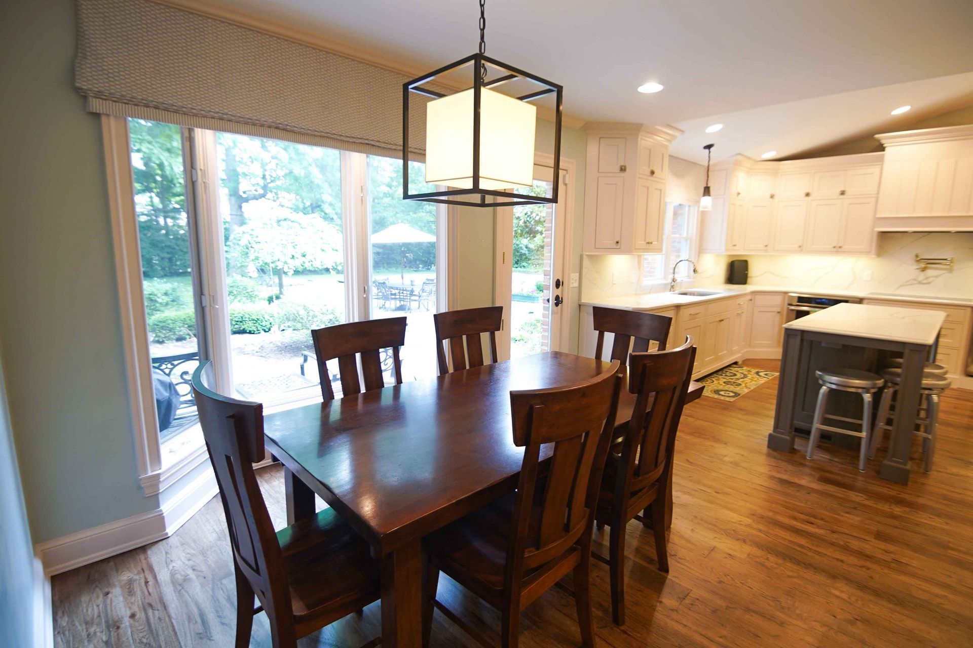 A dining room table and chairs in a kitchen with sliding glass doors.