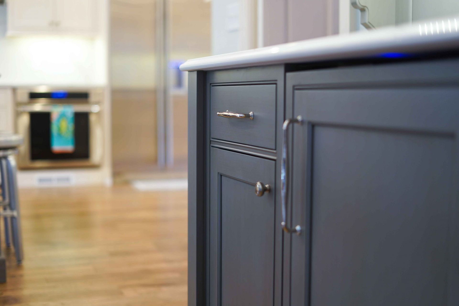 A kitchen with gray cabinets and a white counter top.