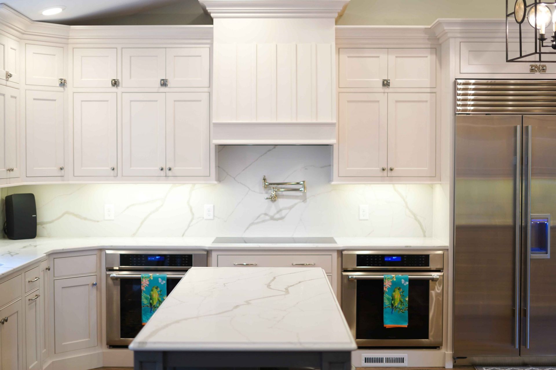 A kitchen with white cabinets , stainless steel appliances , and a large island.