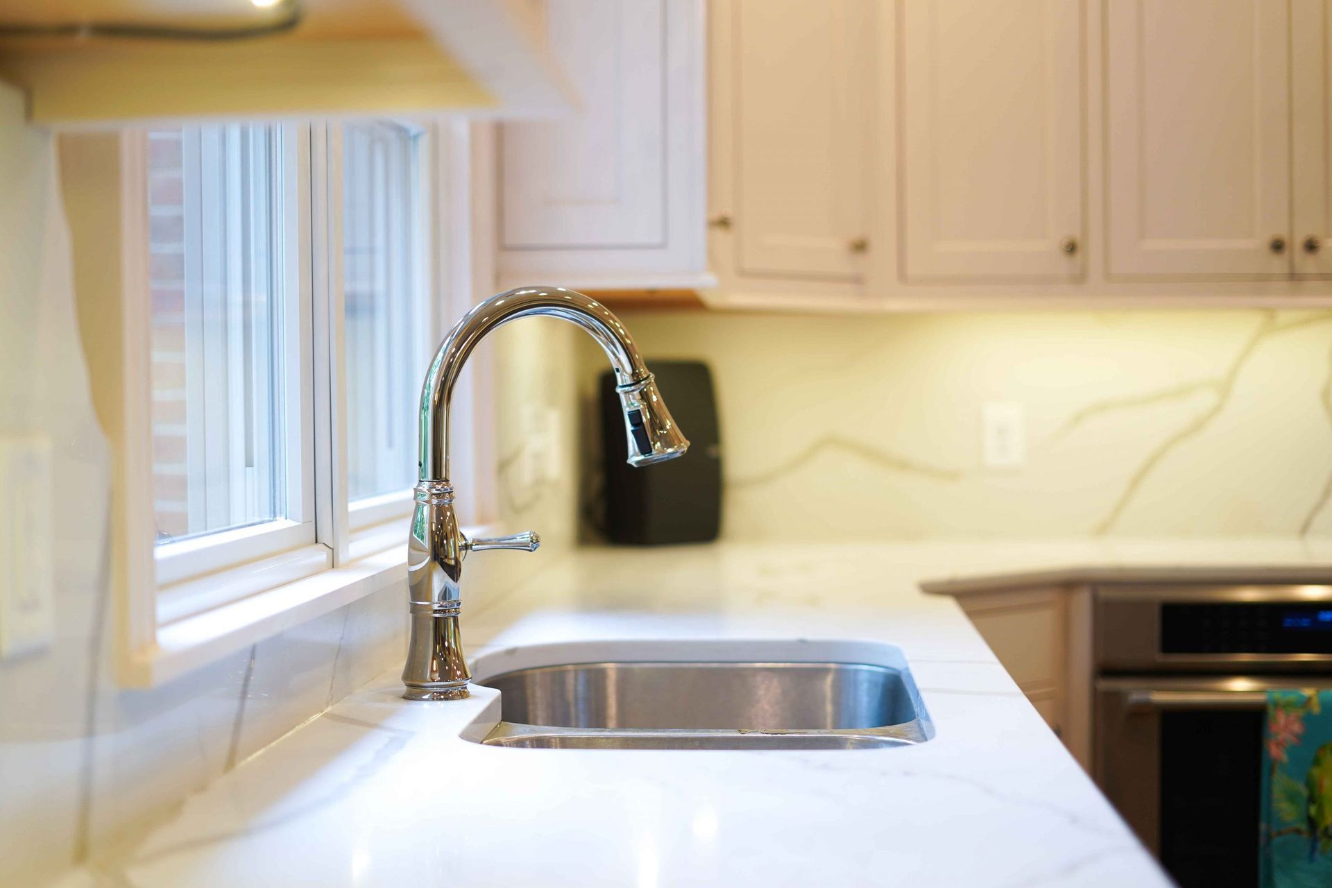 A kitchen sink with a faucet and a window in the background.