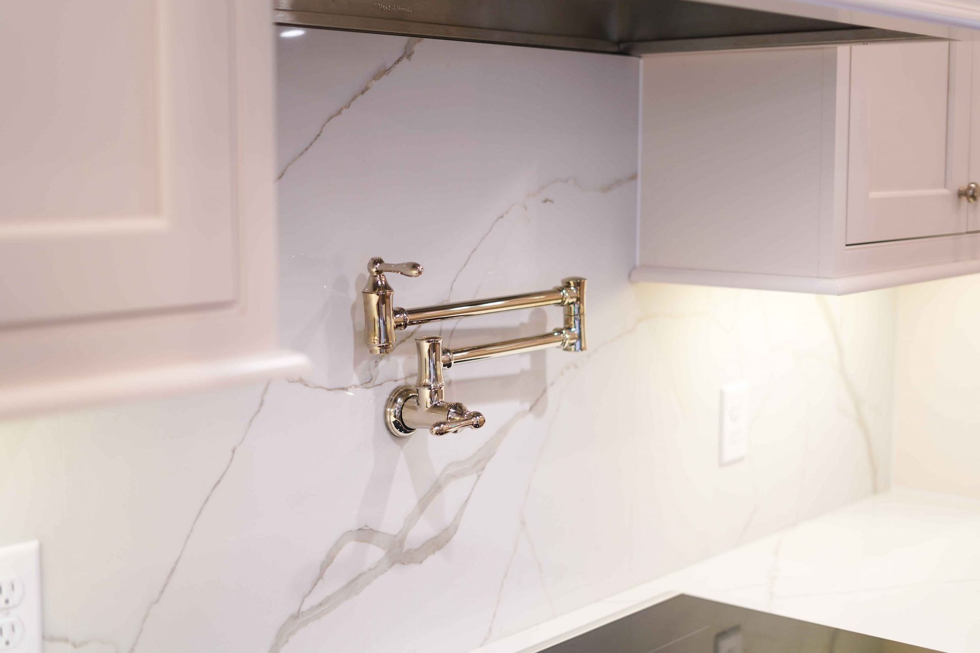 A kitchen with white cabinets and a faucet on the wall.